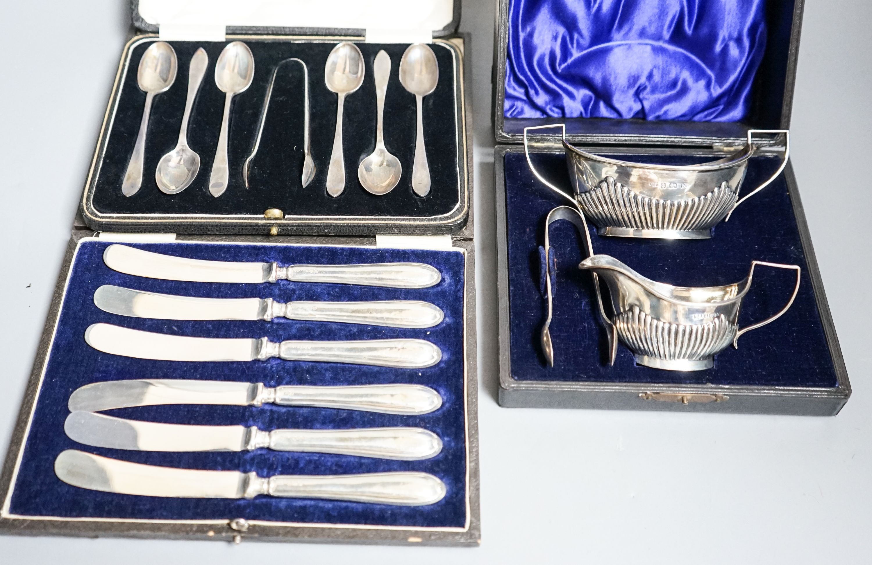 A cased Edwardian silver cream, sugar and sugar tongs, Birmingham, 1901 and two other cased sets of silver cutlery.